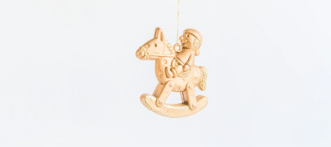 Gold rocking horse ornament hanging from a thread
