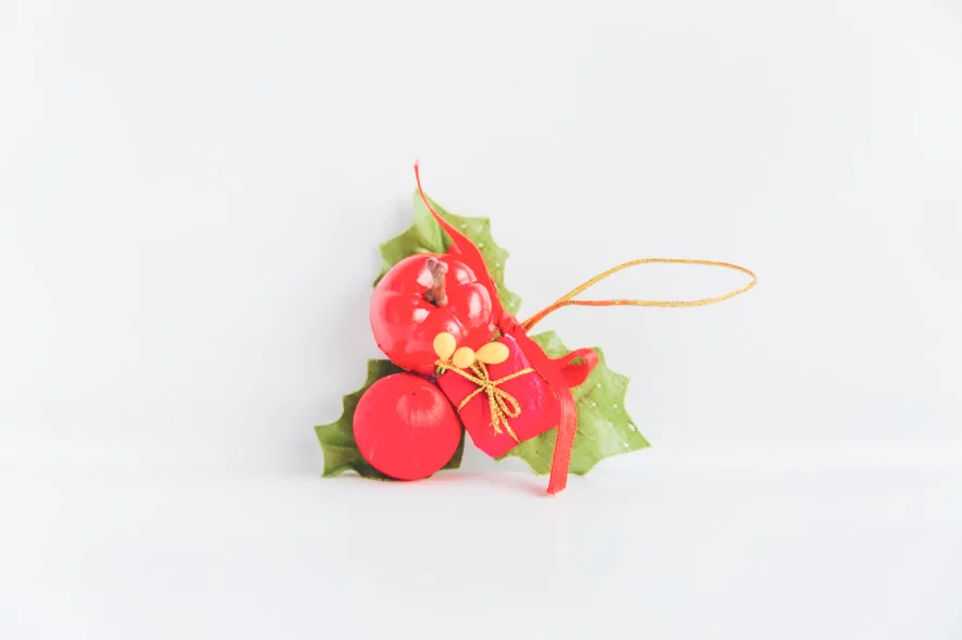 Cluster of red glass baubles with holly leaves and a gold ribbon