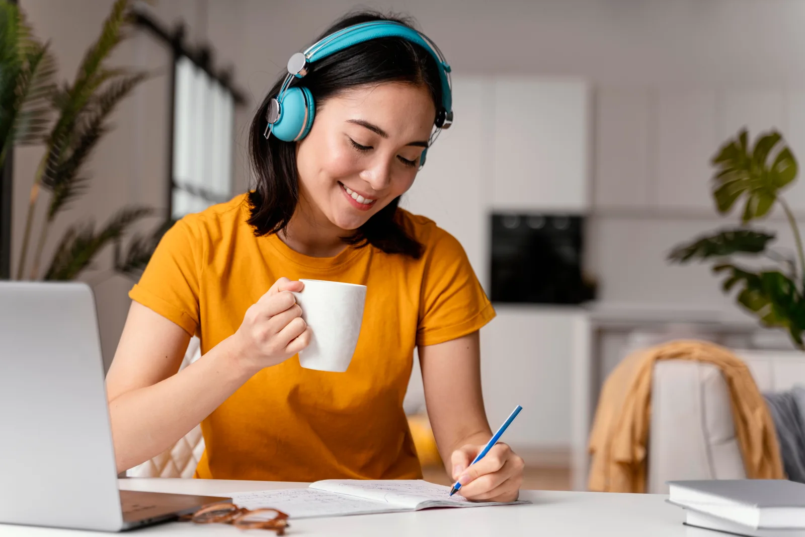 Student in headphones taking notes during an online lesson