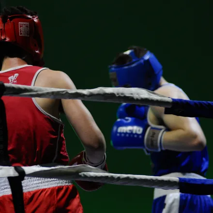 Two boxers sparring in a ring in headgear and gloves