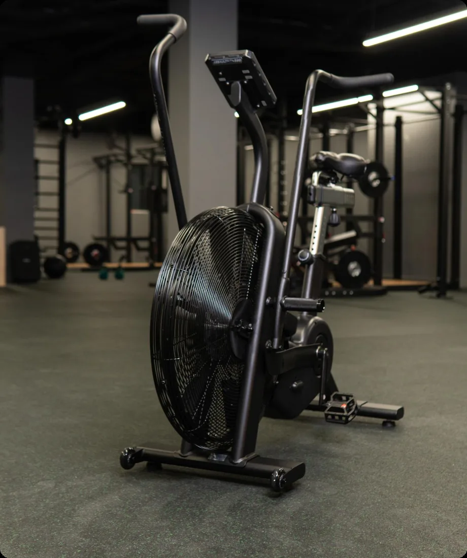 An air bike and free-weight rack on the FORGE training floor