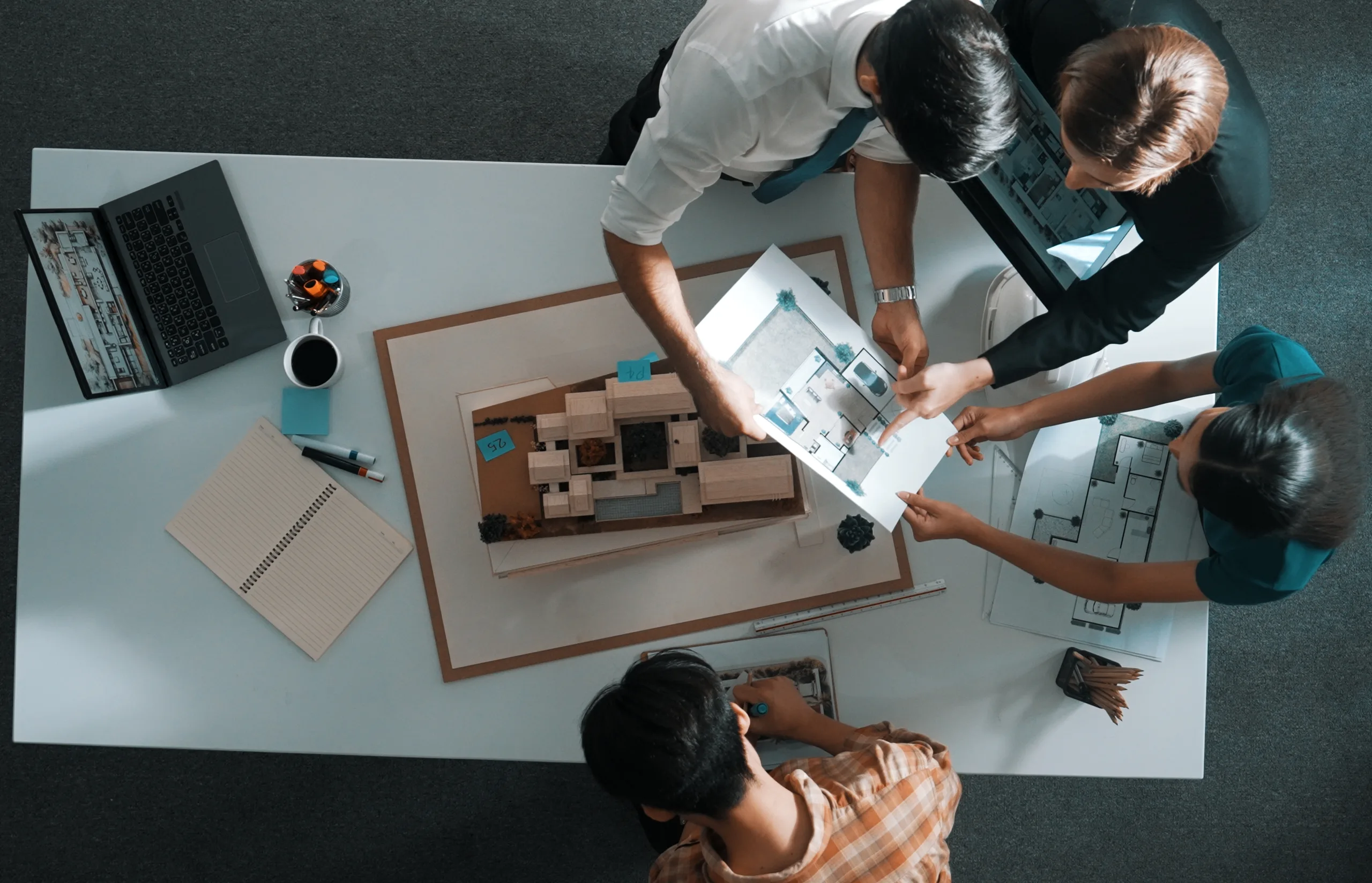 Design team gathered over a floor plan and a scale model of a room