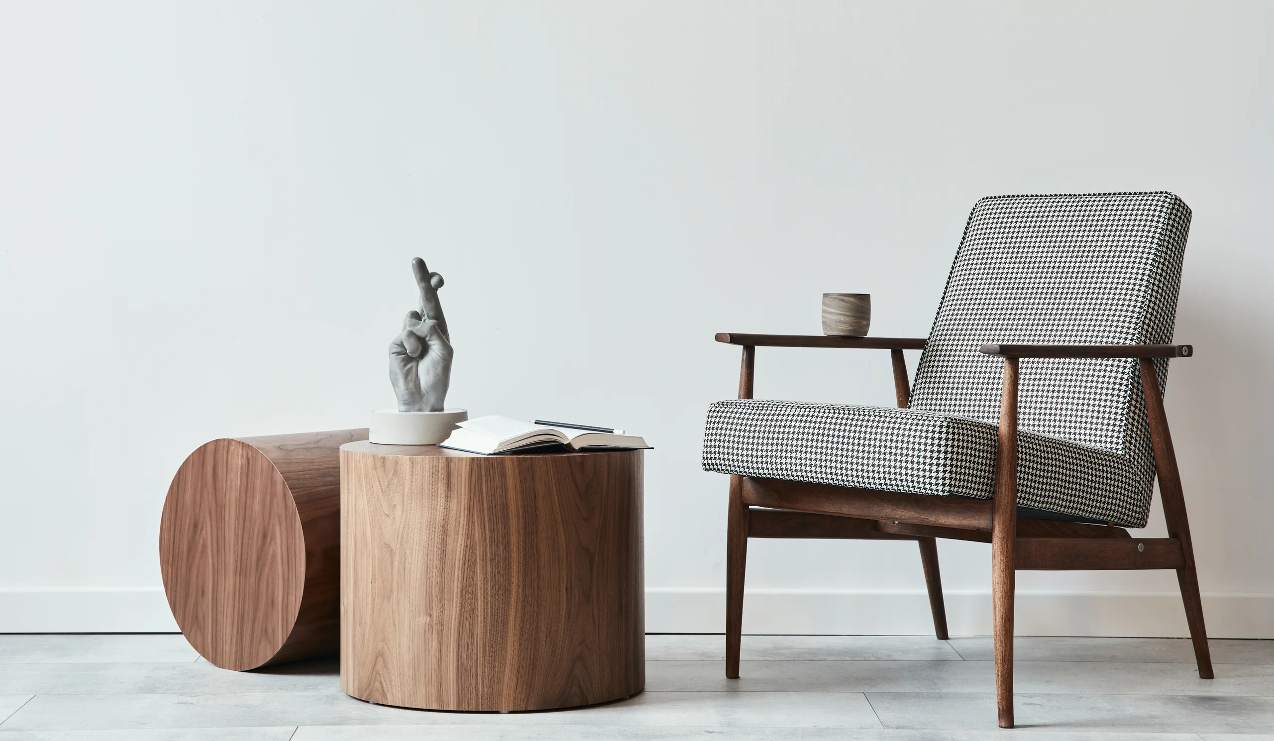 Houndstooth armchair beside a walnut drum table on a pale floor