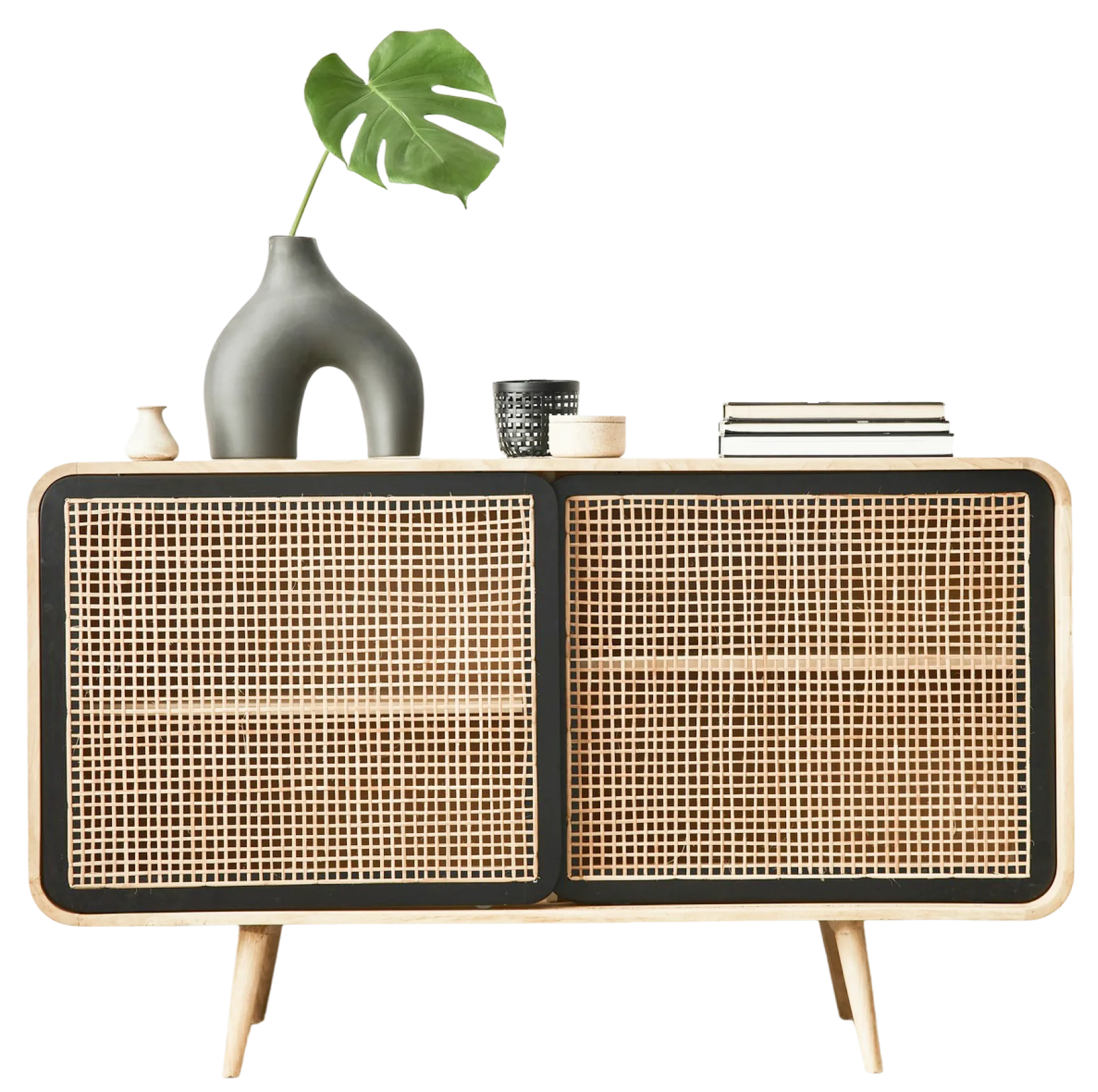 Cane-fronted wooden sideboard with a monstera leaf in a dark vase