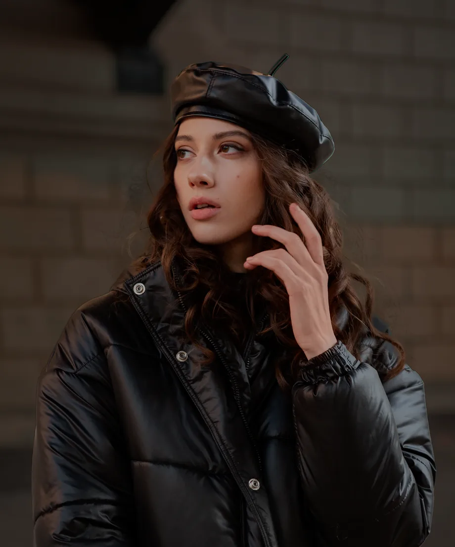 Woman in a black leather beret against a brick wall