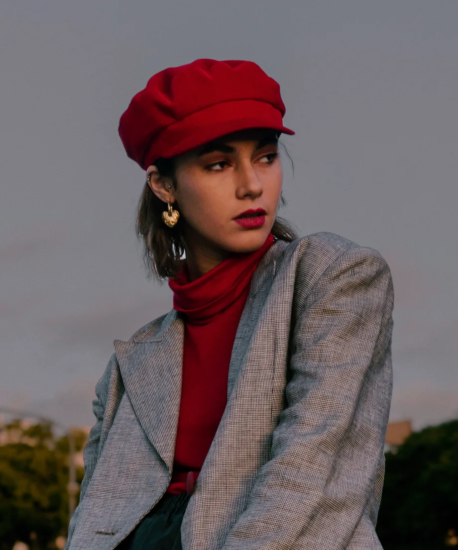 Woman in a red baker boy cap and grey check coat