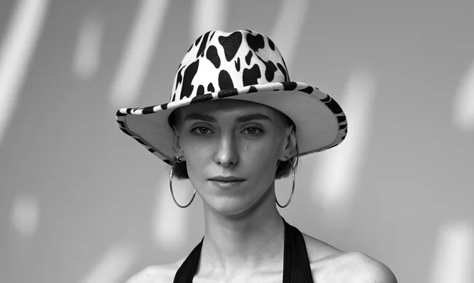 Black and white still of a model in a spotted bucket hat
