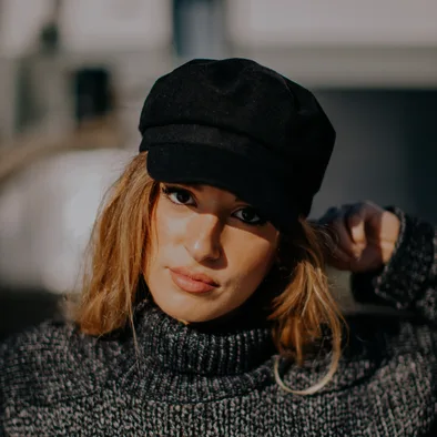 Woman in a black baker boy cap and a knitted turtleneck