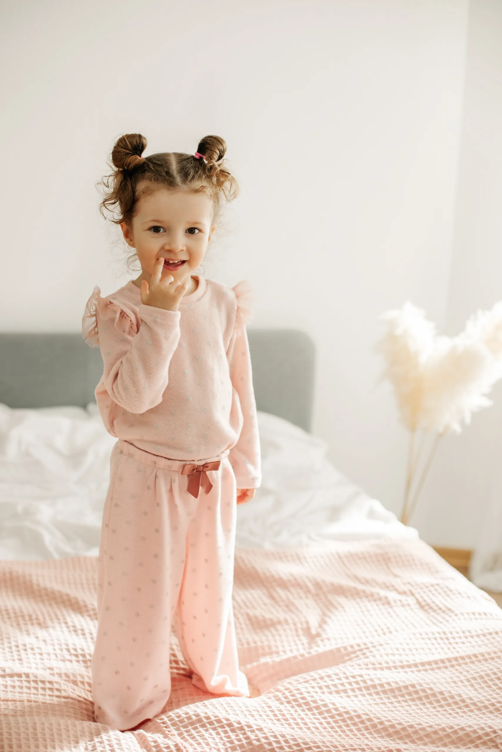 Girl in a pink loungewear set sitting on a bed