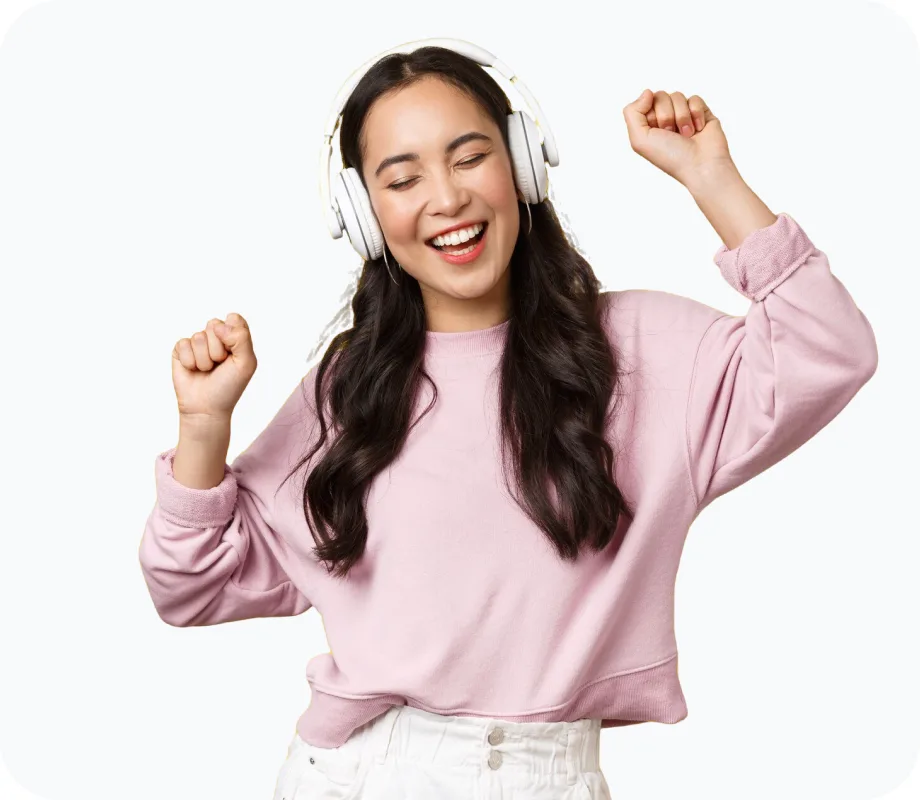 Woman in a pink sweatshirt dancing while wearing white over-ear headphones