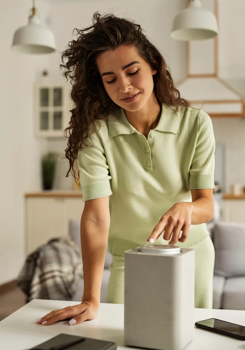 Customer setting up a white smart speaker in her kitchen