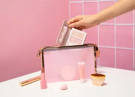 Hand packing a pink cosmetics pouch on a tiled counter